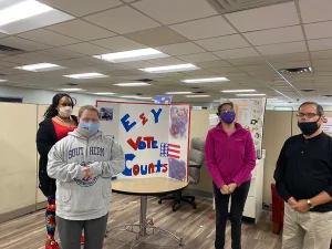 Clients and staff showing off a VOTE sign on National Voter Registration Day